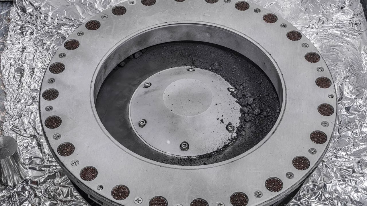 A view of the outside of the OSIRIS-REx sample collector shows material from asteroid Bennu that can be seen on the middle right. Scientists have found evidence of both carbon and water in initial analysis of this material. The bulk of the sample is located inside.