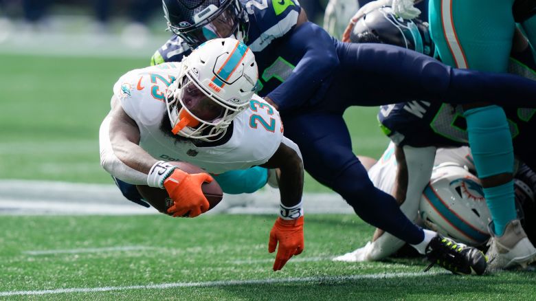 Miami Dolphins running back Jeff Wilson Jr. (23) drives as Seattle Seahawks cornerback Devon Witherspoon (21) defends during the first half of an NFL football game Sunday, Sept. 22, 2024, in Seattle. (AP Photo/Stephen Brashear)