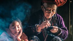A woman from the Red Dao minority, in L√†o Cai Province, northwest Vietnam doing some embroidery at the door of her property, with her great-granddaughter alongside her. The Red Dao are one of the most distinctive of the ethnic groups, and largely due to their headdresses. They are known for their intricate embroidery - a skill which is passed down from mother to daughter and on down to further generations of the family.