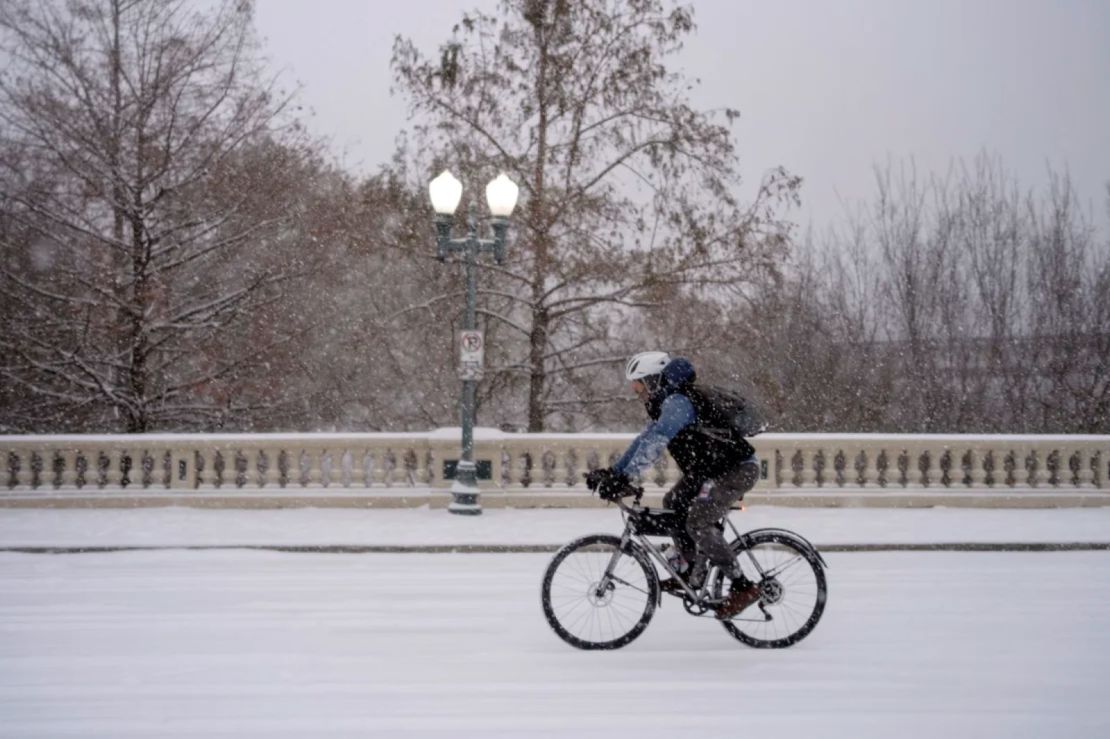 Un hombre anda en bicicleta por el puente de Sabine Street cerca del centro mientras una tormenta invernal trae intensas bandas de nieve y aguanieve el martes en Houston.