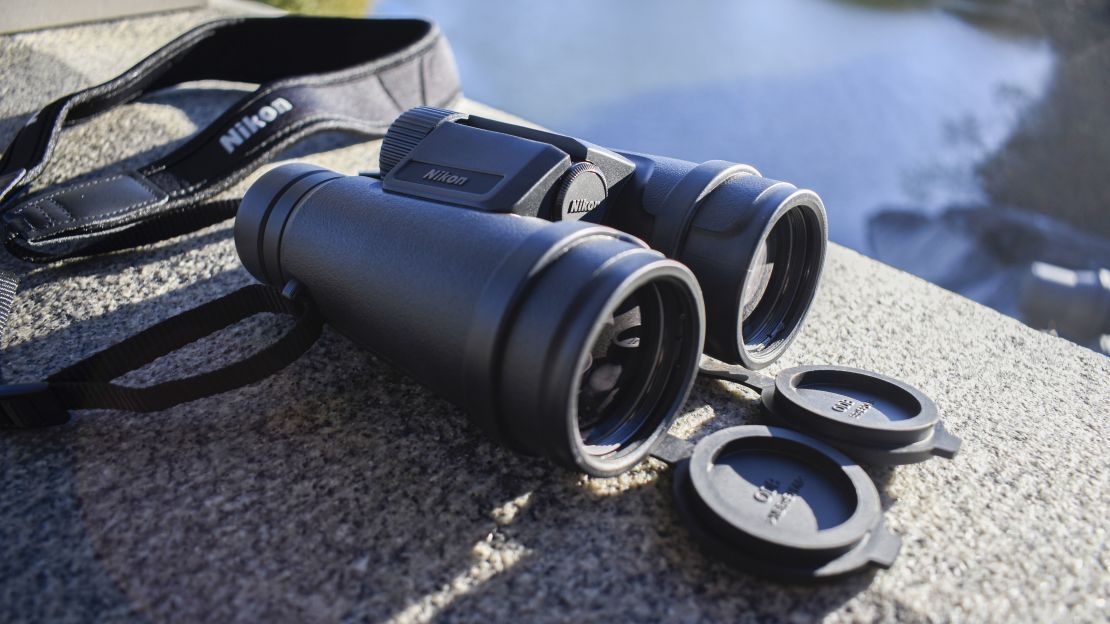 Black binoculars rest on a stone wall.