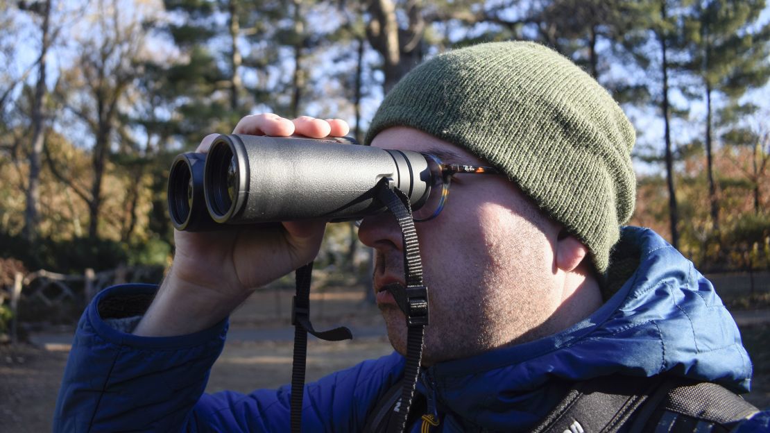 A person looking through a pair of black binoculars.