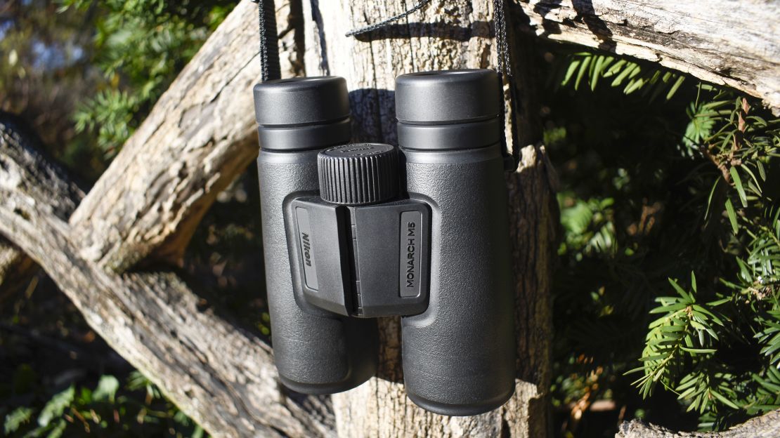 Black binoculars hanging from a fence post.