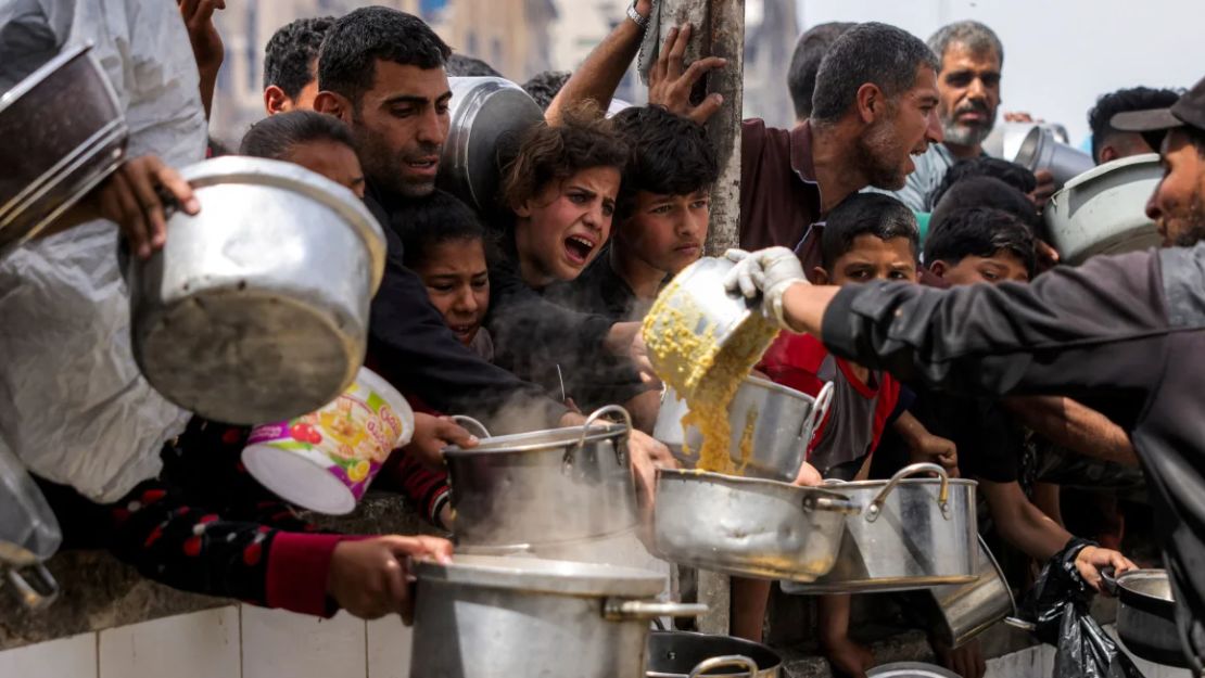 La gente hace cola con ollas para recibir comidas benéficas de una cocina en Beit Lahia, en el norte de Gaza, el 24 de abril.