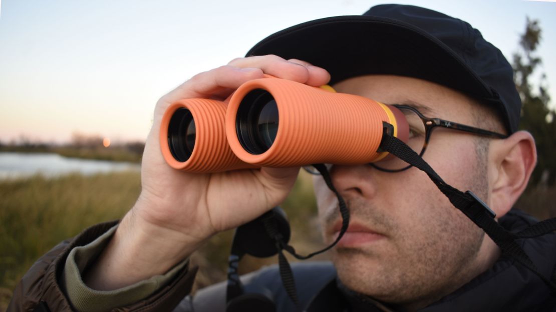 A person looking through orange binoculars.