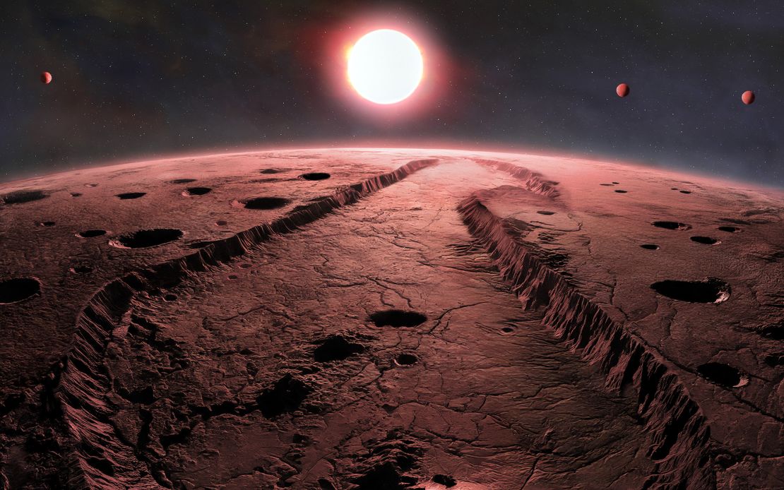 Een illustratie geeft weer hoe het oppervlak van een van de exoplaneten die van Barnard's ster in een baan kunnen zien. De andere drie planeten binnen het systeem zijn ook te zien.