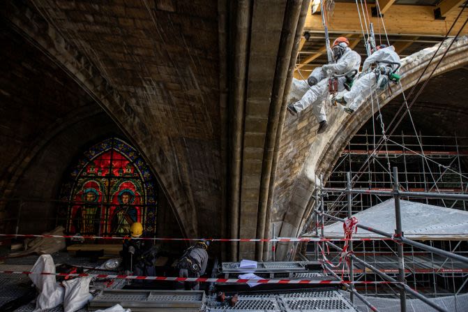 Los trabajadores colocan piedra en yeso mientras descienden en rápel por una bóveda dentro de Notre Dame en abril de 2021.