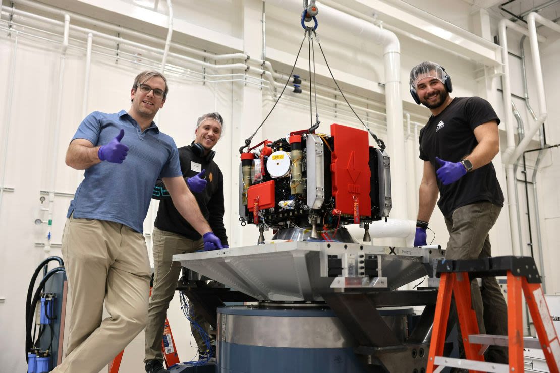 Empleados de AstroForge posan con la nave espacial Odin durante el proceso de desarrollo y pruebas.