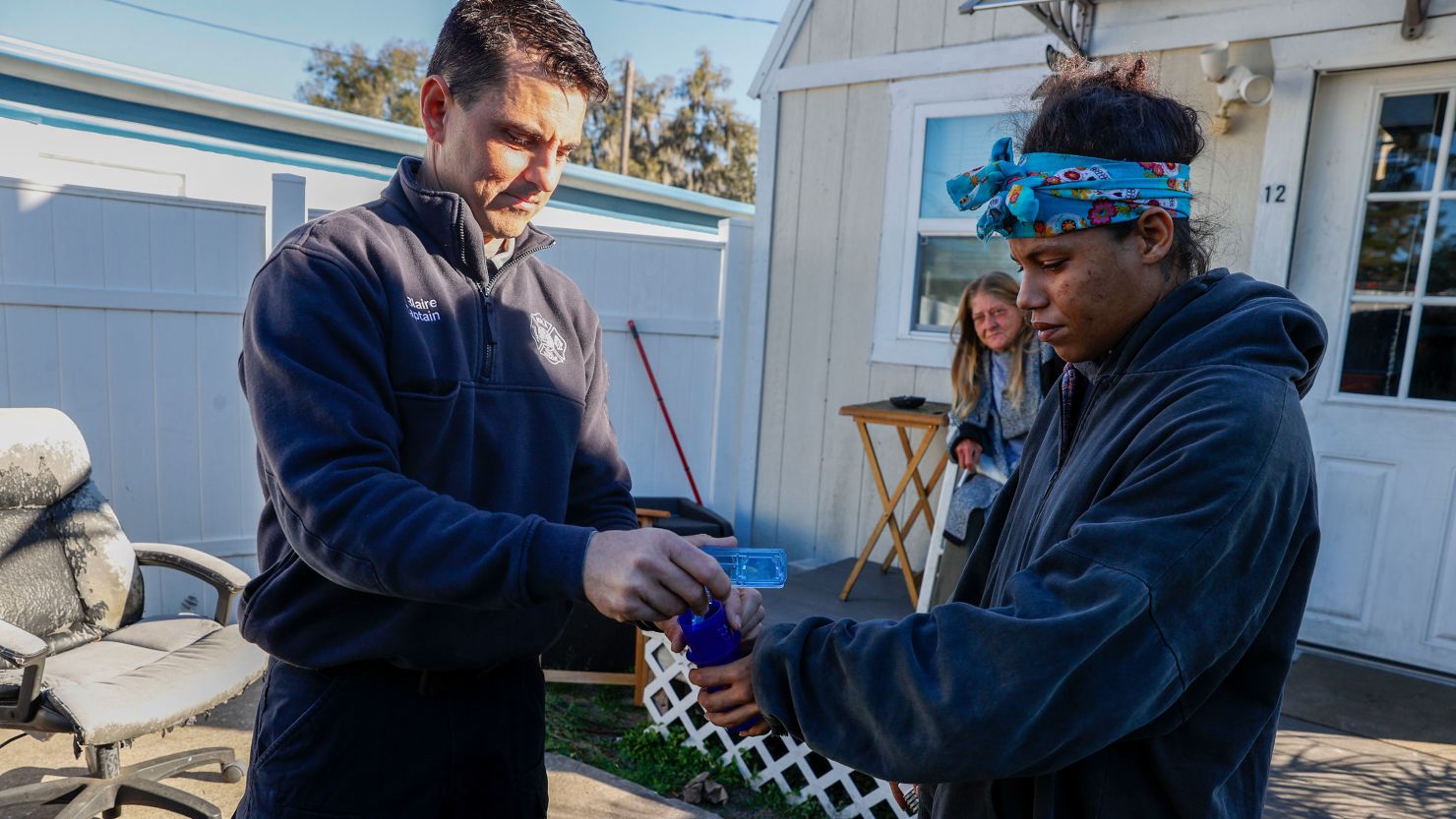 Ocala Fire Rescue EMS Capt. Jesse Blaire gives medication to Shawnice Slaughter, who is working to recover from a substance use disorder through Florida's Coordinated Opioid Recovery Network, at her home.