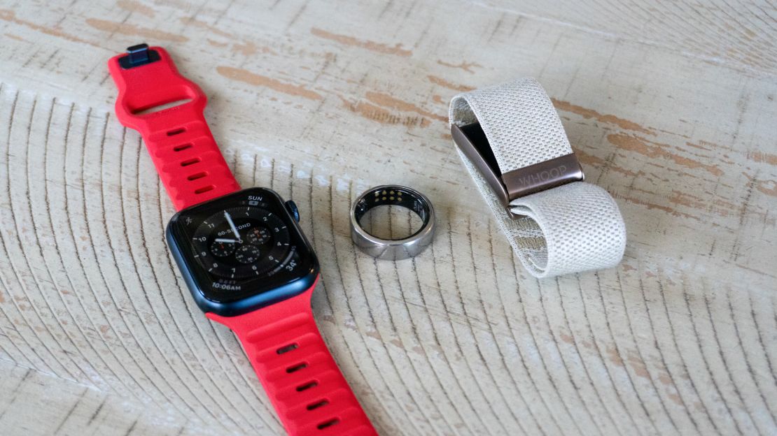 Three wearable fitness trackers on a wooden surface.