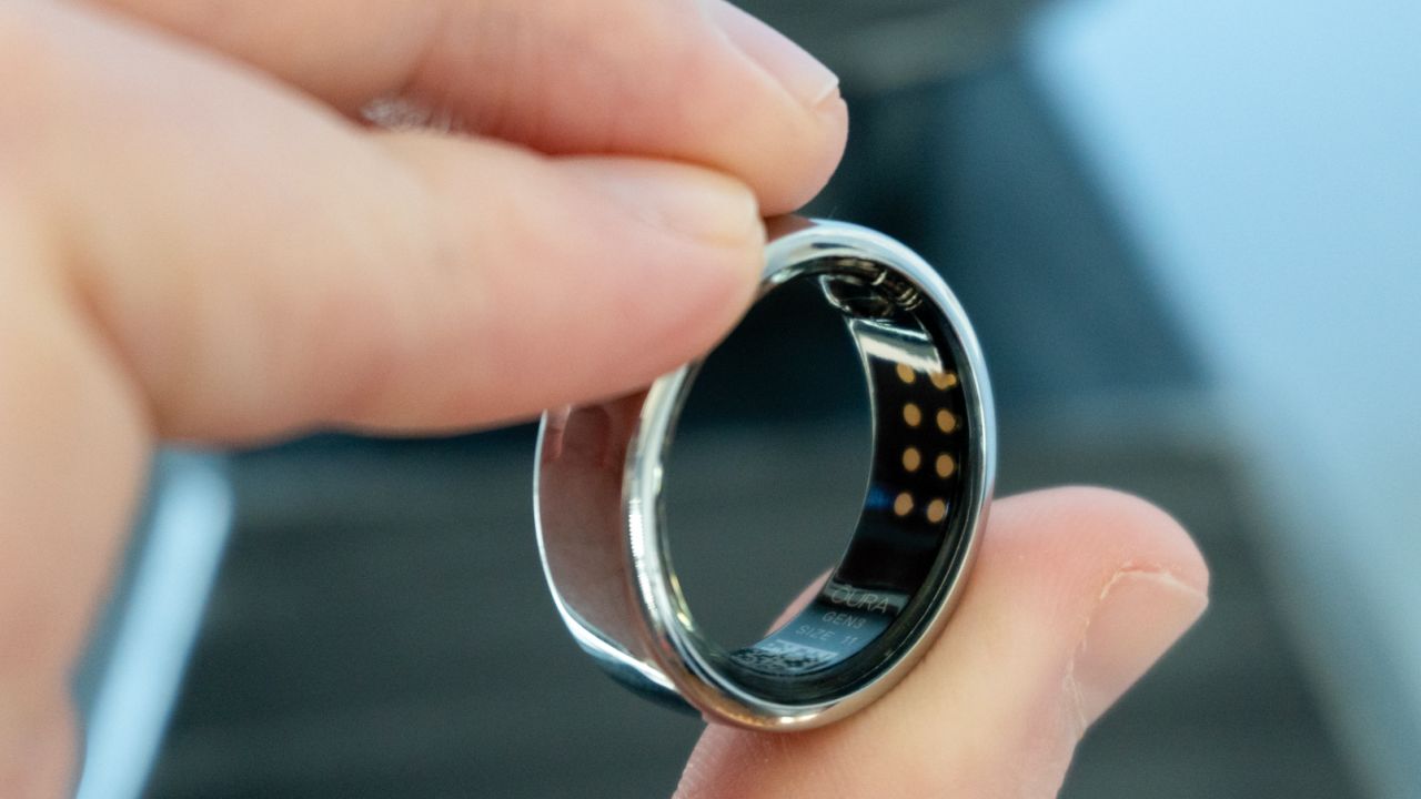 A hand holding an Oura Ring reveals the ring's interior.