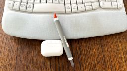 oxo cleaning brush resting on wireless keyboard next to airpods pro