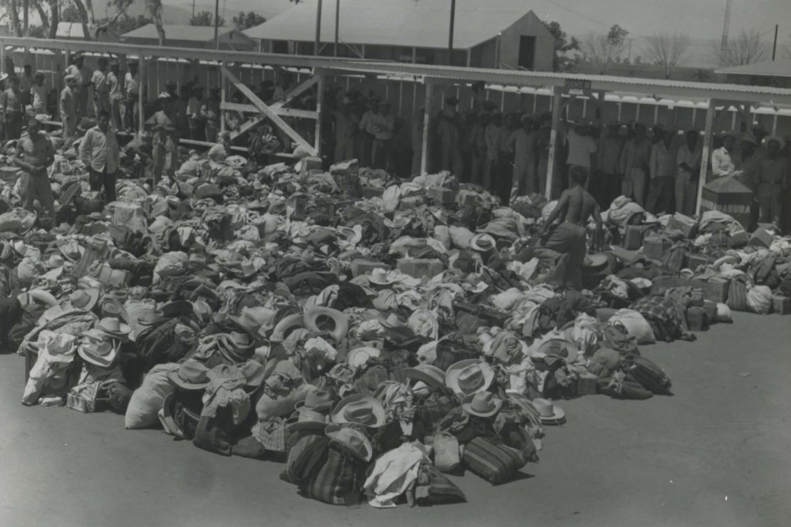 Aspiring <em>braceros</em> line up to undergo physical examinations by the US Public Health Service in South Texas in the 1950s. Their hats, bags and other belongings are piled nearby.