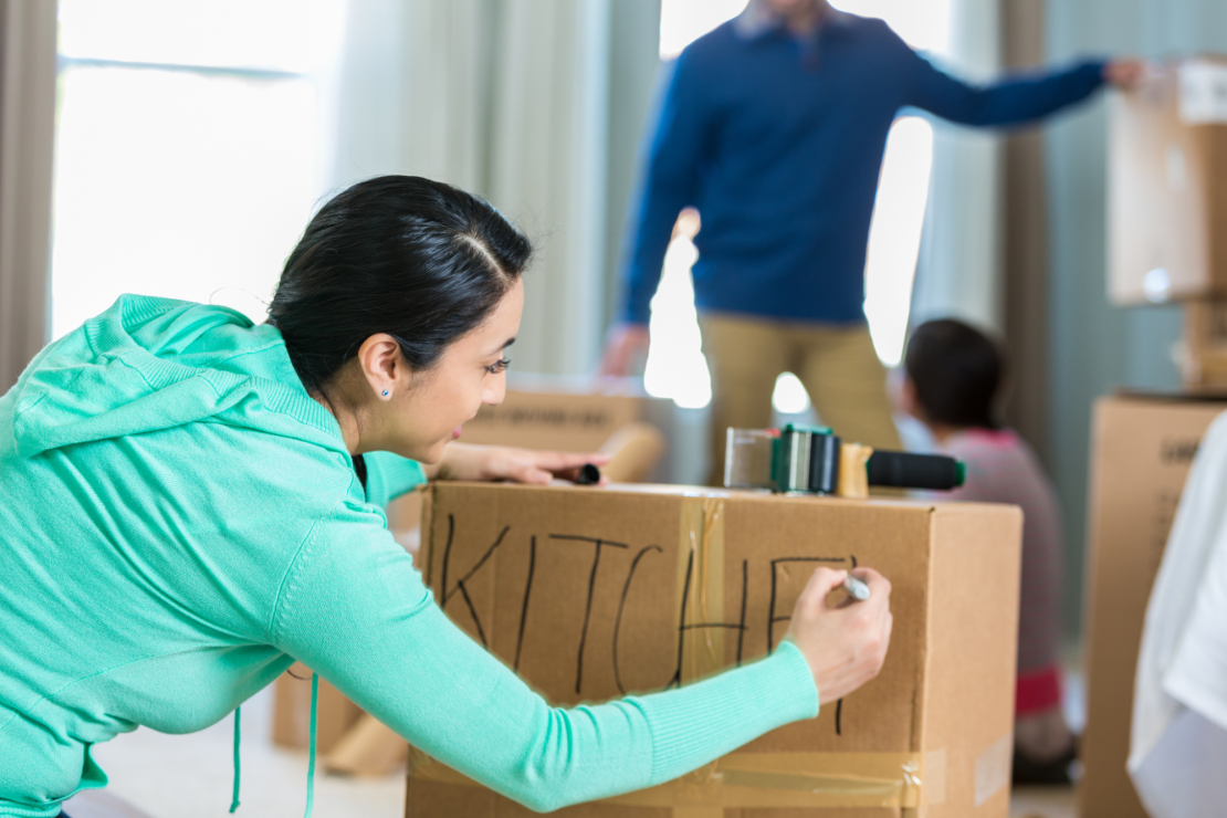 Woman labels a moving box.