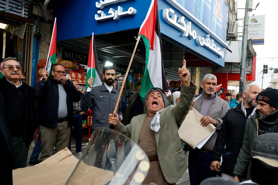 La gente sostiene banderas palestinas durante una manifestación contra el tiroteo entre las fuerzas de seguridad de la autoridad y militantes en el campamento de Jenin.