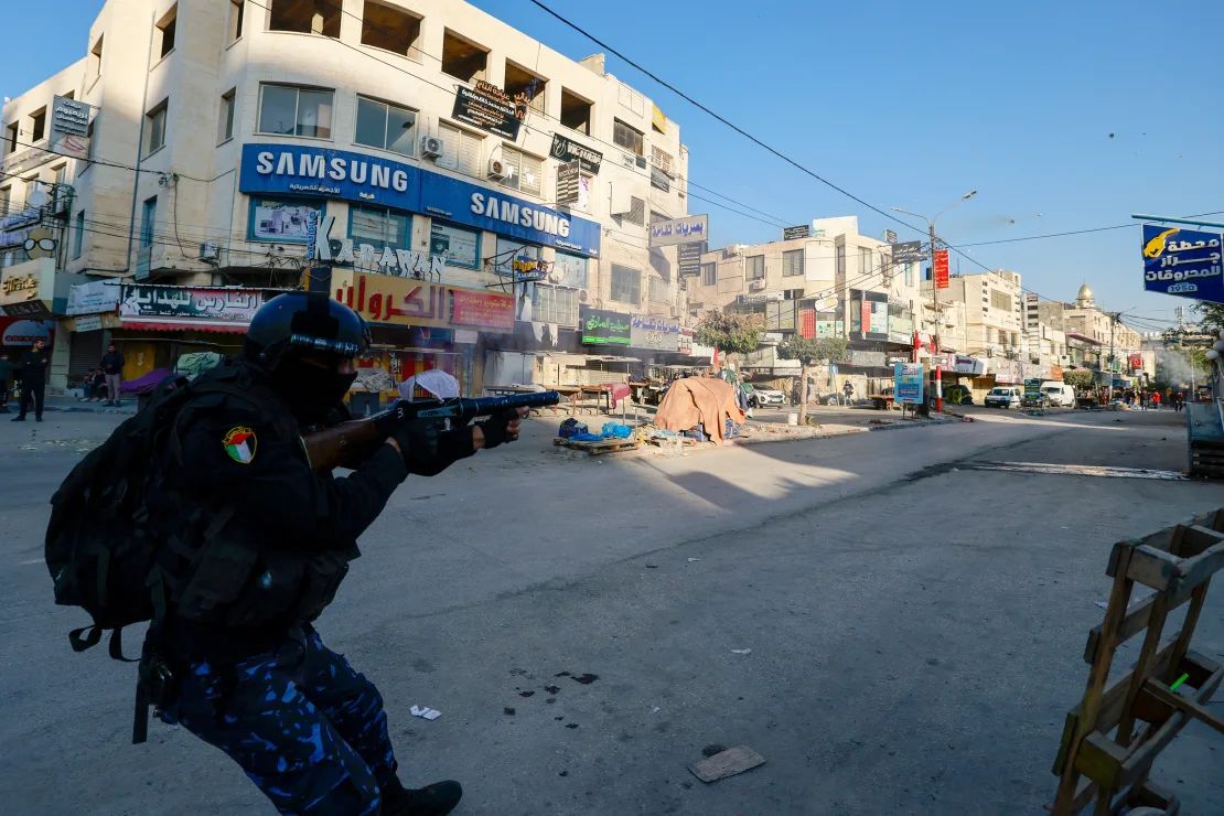 Un miembro de las fuerzas de seguridad de la Autoridad Palestina dispara gases lacrimógenos hacia una protesta contra su operación de seguridad en Jenin.