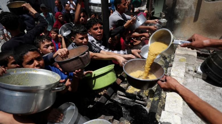Palestinos esperan recibir comida cocinada por una cocina benéfica, en Jabalia en el norte de Gaza, el 19 de mayo de 2025.