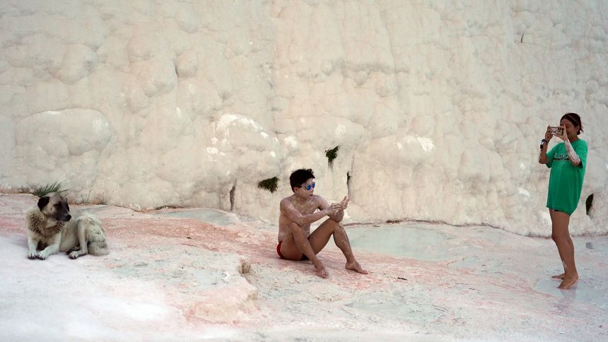 Korean tourist DJ Tiz gets muddy as Fre Nas and a local dog look on.