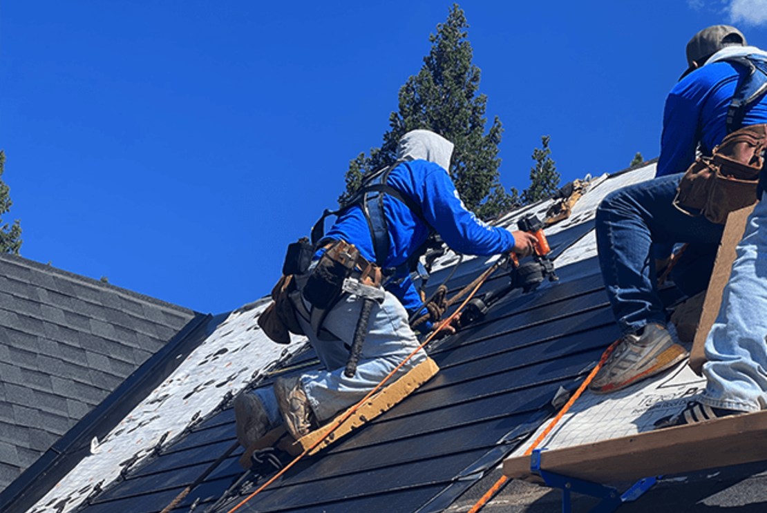 Two workers installing solar shingles