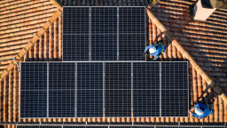 Aerial view of two workers installing solar panels on a house roof