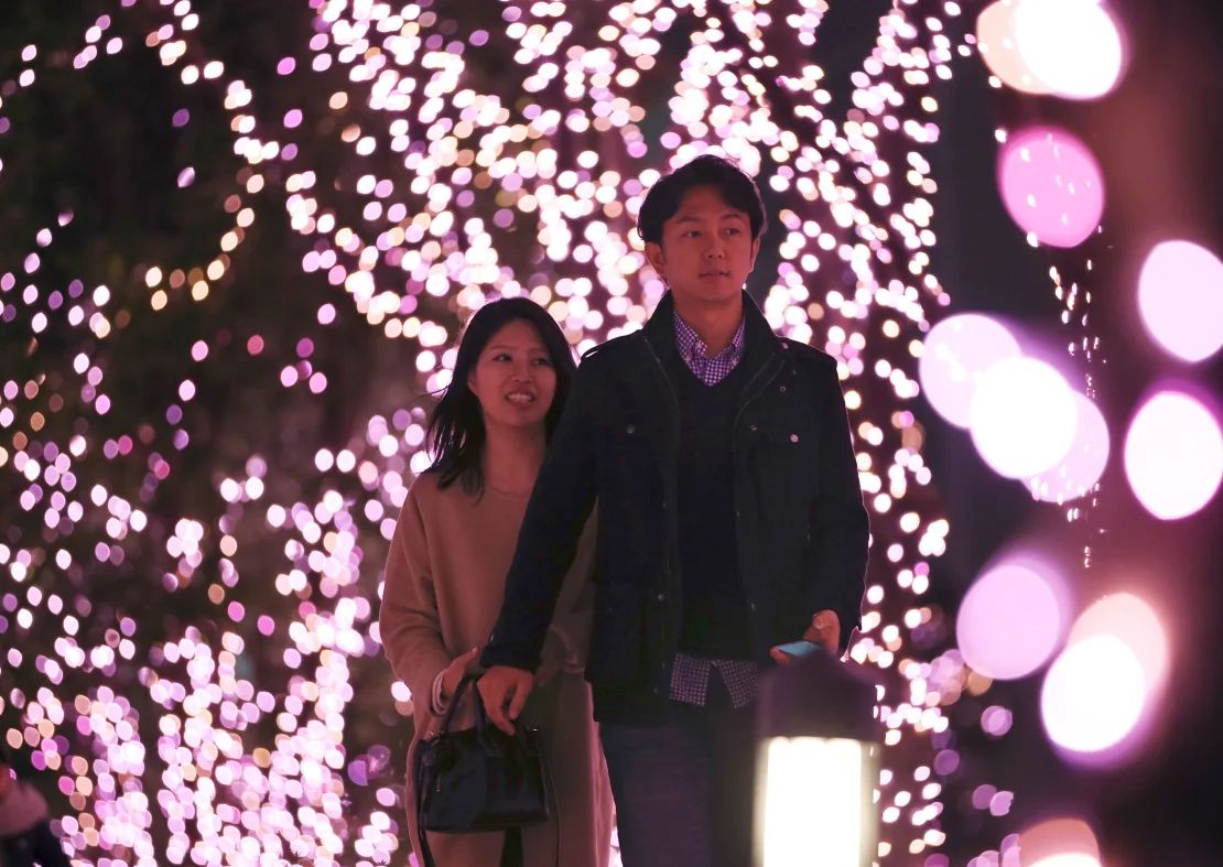 Una pareja camina entre las luces navideñas en una zona comercial de Tokio.