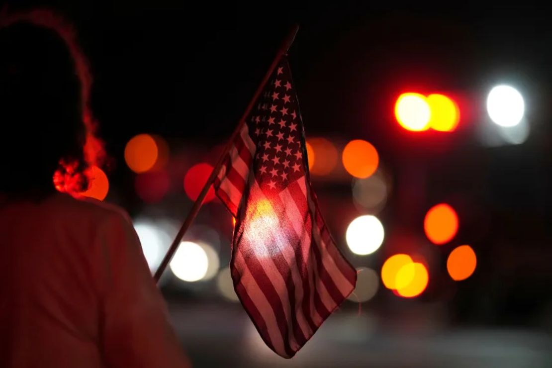 Una persona sostiene una bandera estadounidense en una procesión en memoria de los agentes de policía asesinados en una zona rural de Pensilvania el miércoles.