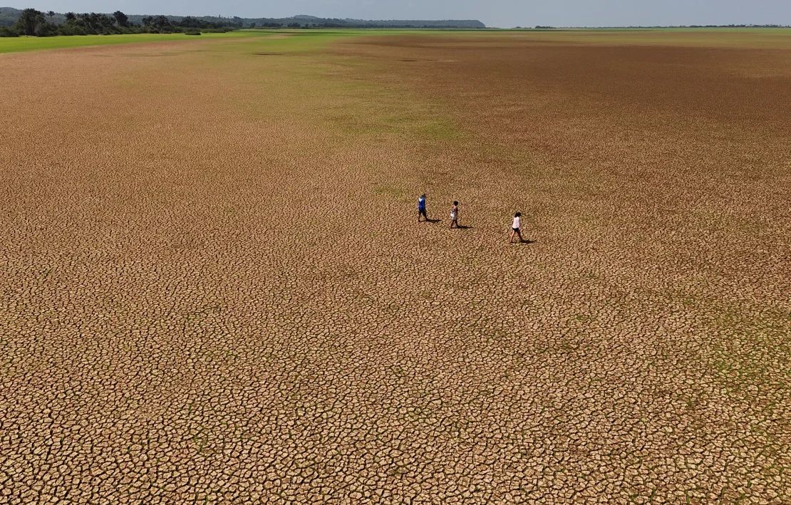 People walking on the dry bed of the Tapajos river during an intense drought, in the National Tapajos forest, Paraá state, Brazil, on October 10, 2024.