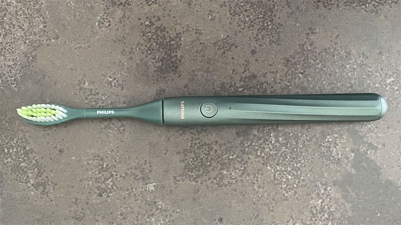 The Philips One by Sonicare electric toothbrush on a stone countertop