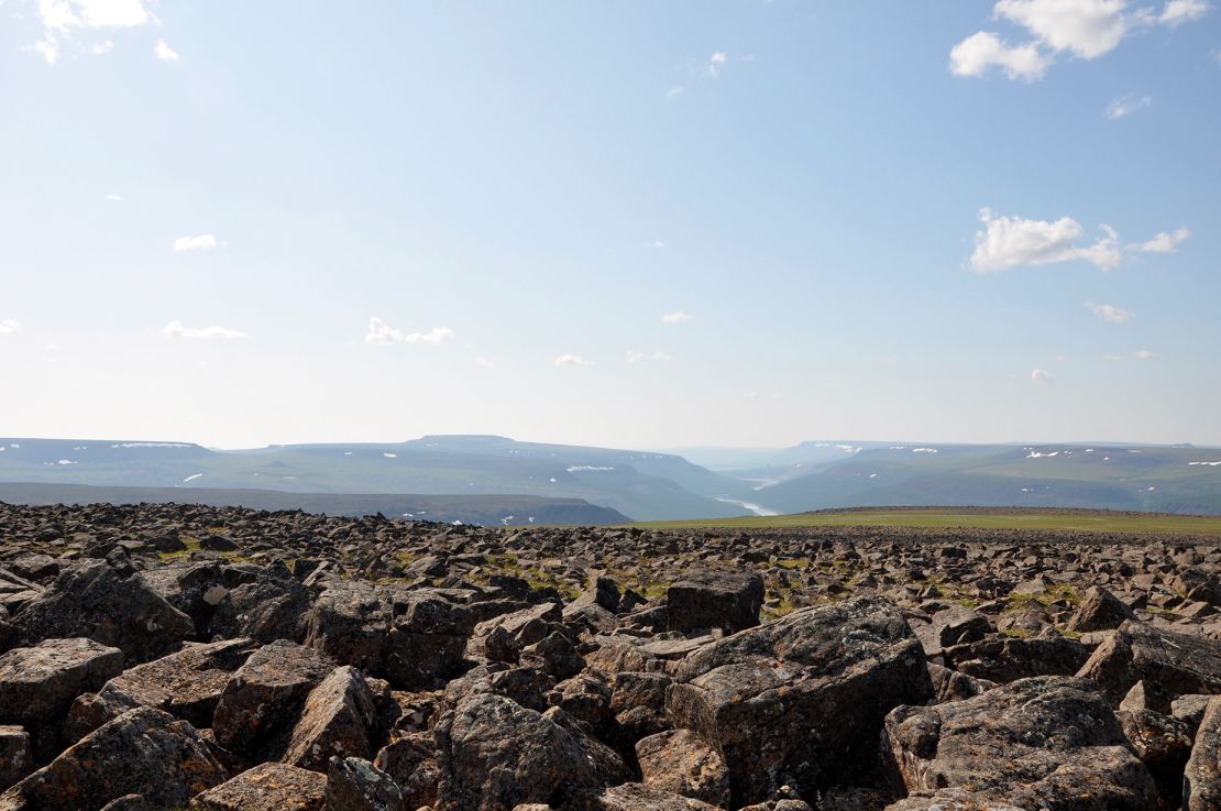 The Siberian Traps was a vast area of volcanic activity in Eurasia that led to the biggest mass extinction 252 million years ago. The distant mountains are remains of basalt lava flows, and the Maymecha river can be seen amid the thick volcanic layers. The foreground is also the rubbly top of the volcanic landscape.