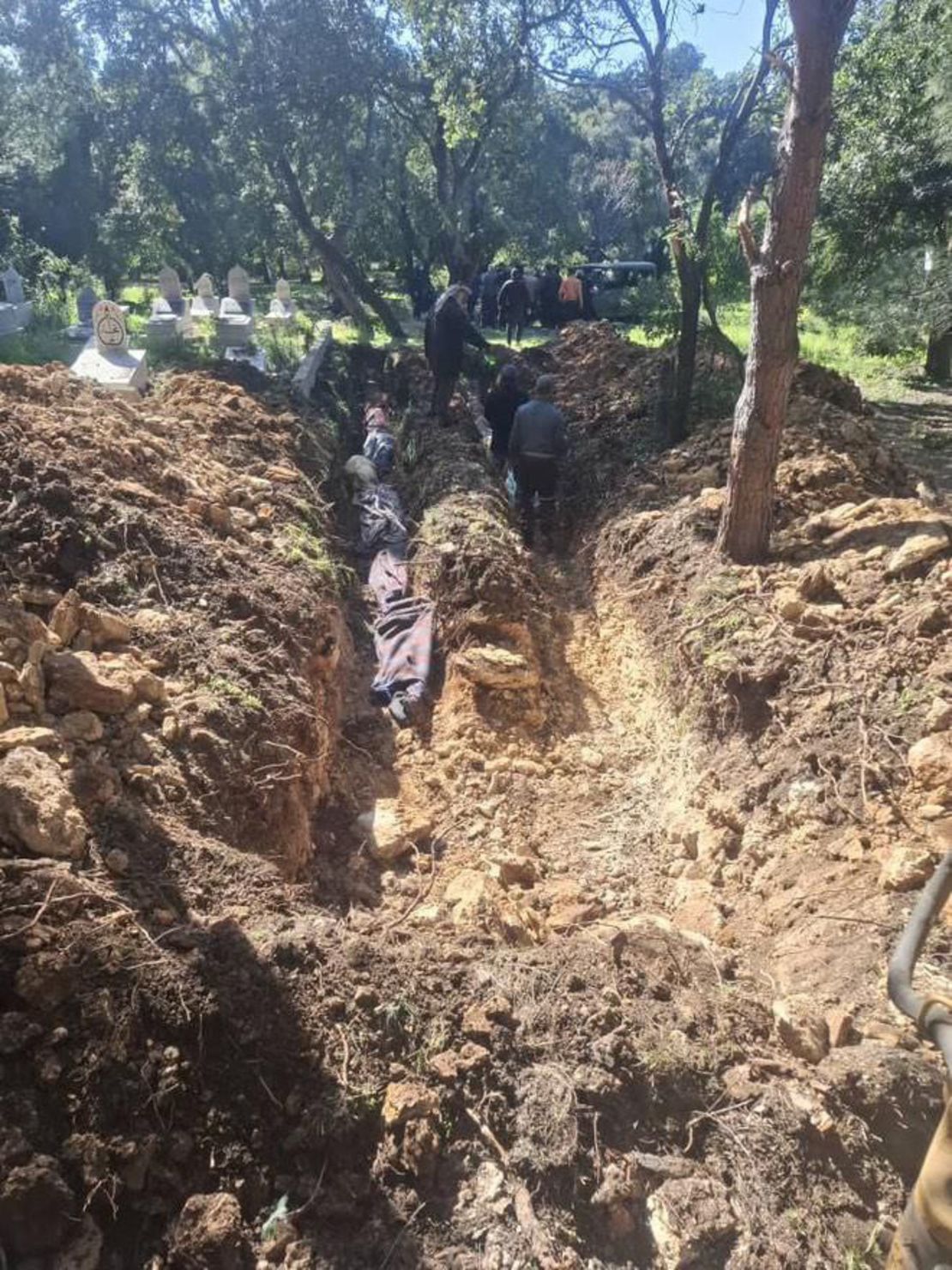 Bodies are laid in a mass grave in Pine village.