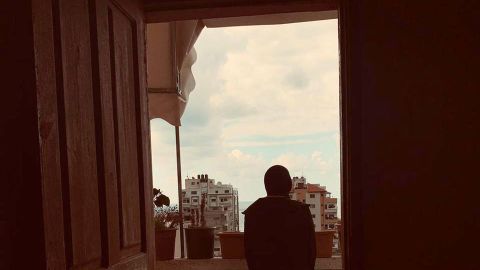 A Palestinian student stands on her best friend's balcony, before the war in Gaza began.