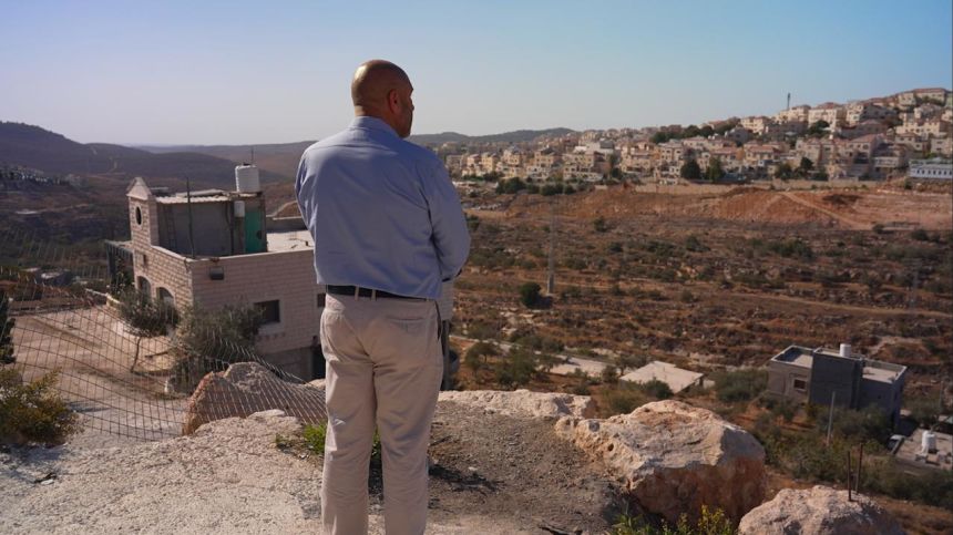Ahmad Shakarna looks out at a 30-year-old illegal Israeli settlement that stands above his family's hundred-year-old olive groves.