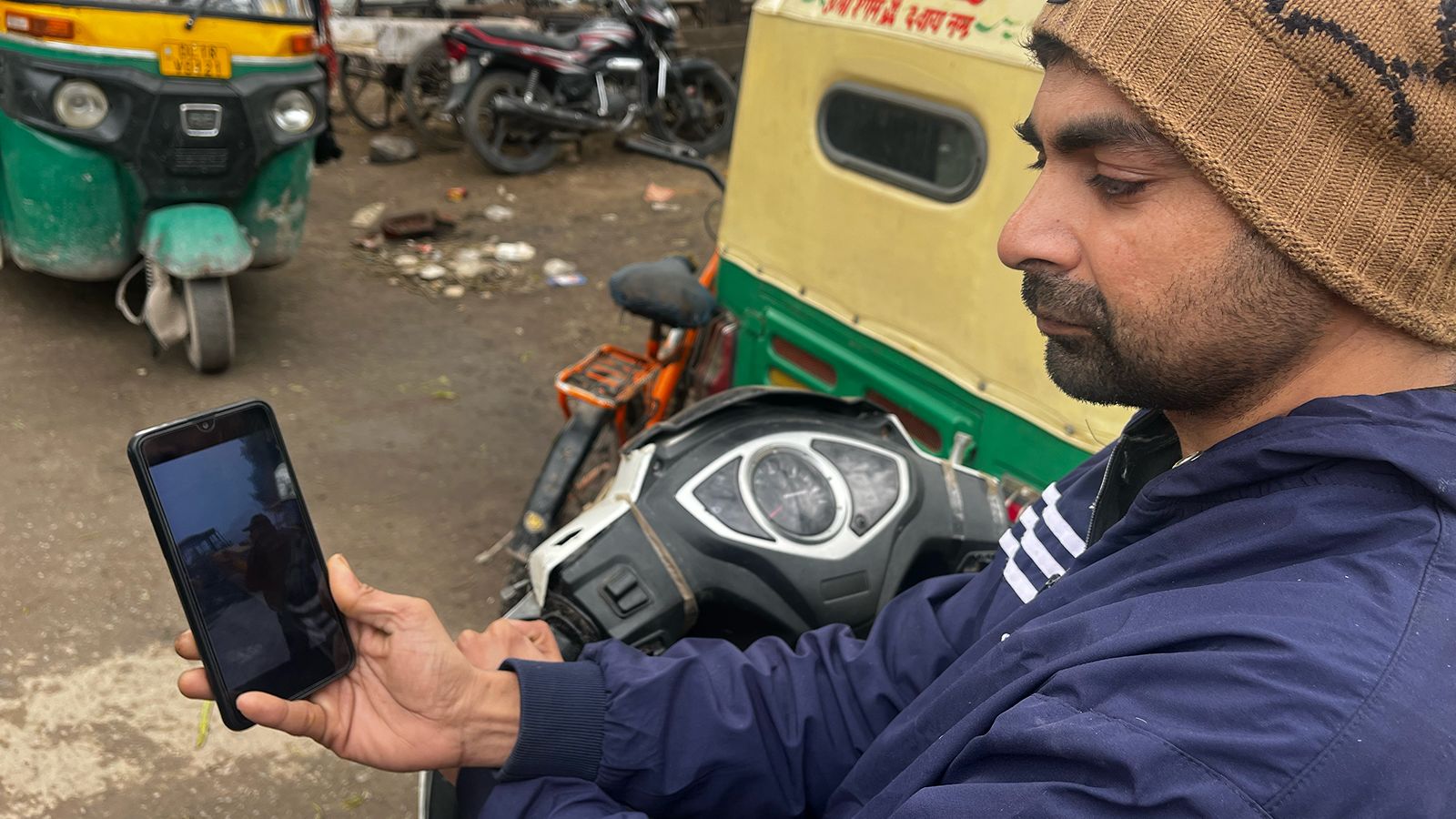 Mohammad Aman, a 32-year-old Salon worker from Delhi, looks at photos of the mosque demolition on his phone.