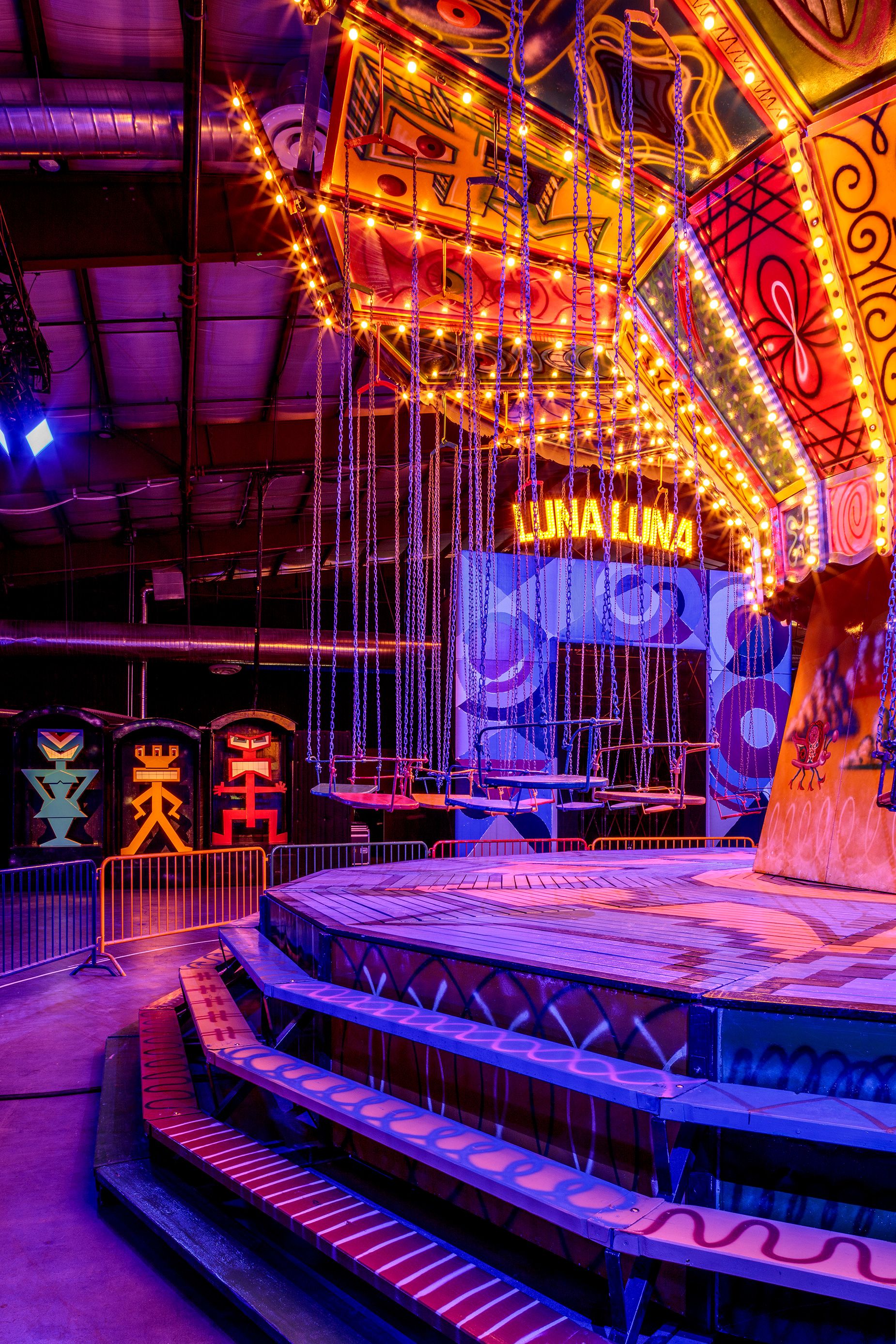 Carnival lights illuminate a trippy chair swing ride by Kenny Scharf, one of Luna Land's statement rides.