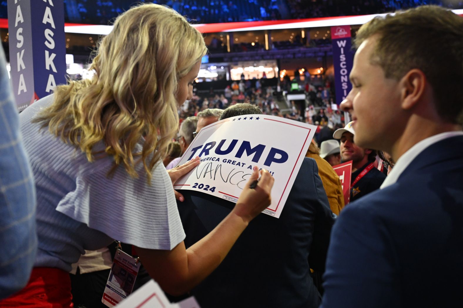 A delegate writes Vance's name on a Trump campaign sign on Monday.