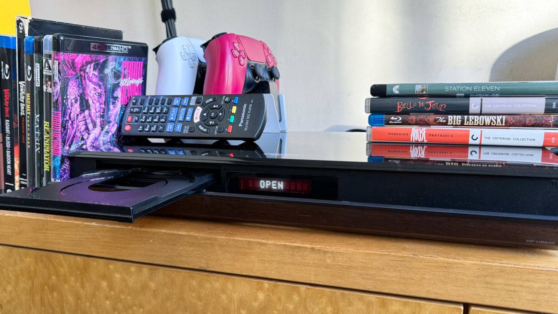 An open Blu-ray player on a wooden table.