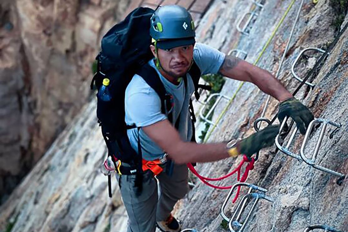 Xue Ke, the owner of Gushi Cliff Coffee, climbs on the cliff face.