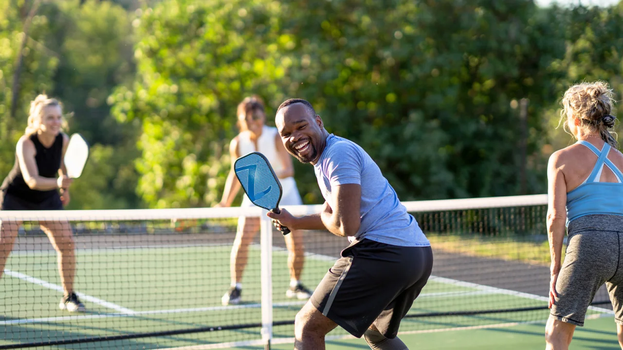Four people playing pickleball and smiling.