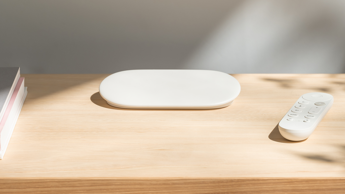 The porcelain white google tv streamer and remote on a countertop.