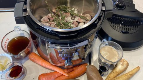 An Instant Pot electric pressure cooker open, on a counter, surrounded by stew ingredients.