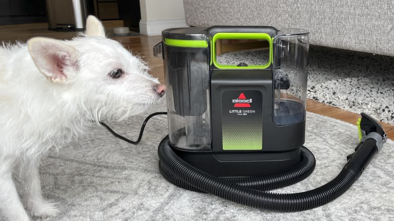 dog sniffing a bissell vacuum on the floor next to it