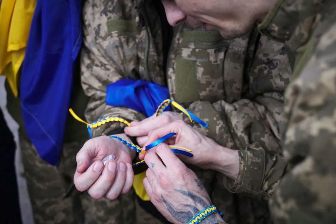 Presos ucranianos liberados el viernes se atan a las muñecas pulseras del color de la bandera ucraniana.