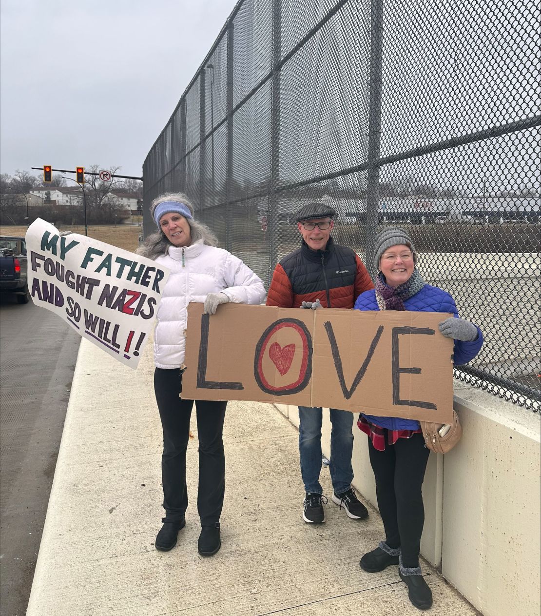 Kim Lachance and other demonstrators hold positive signs on the same overpass Saturday.