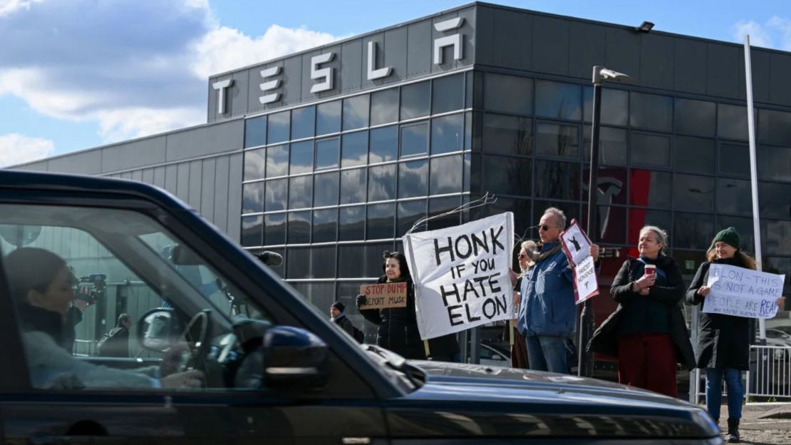 Manifestantes sostienen carteles en contra de Tesla durante una protesta que anima a la gente a boicotear la empresa en oposición a las iniciativas políticas de su director ejecutivo, Elon Musk, frente al Tesla Centre Park Royal en Londres, Reino Unido.