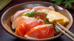 Japanese donburi rice bowl with caviar, salmon meat, scrambled eggs and leaf on a plate, traditional Asian food