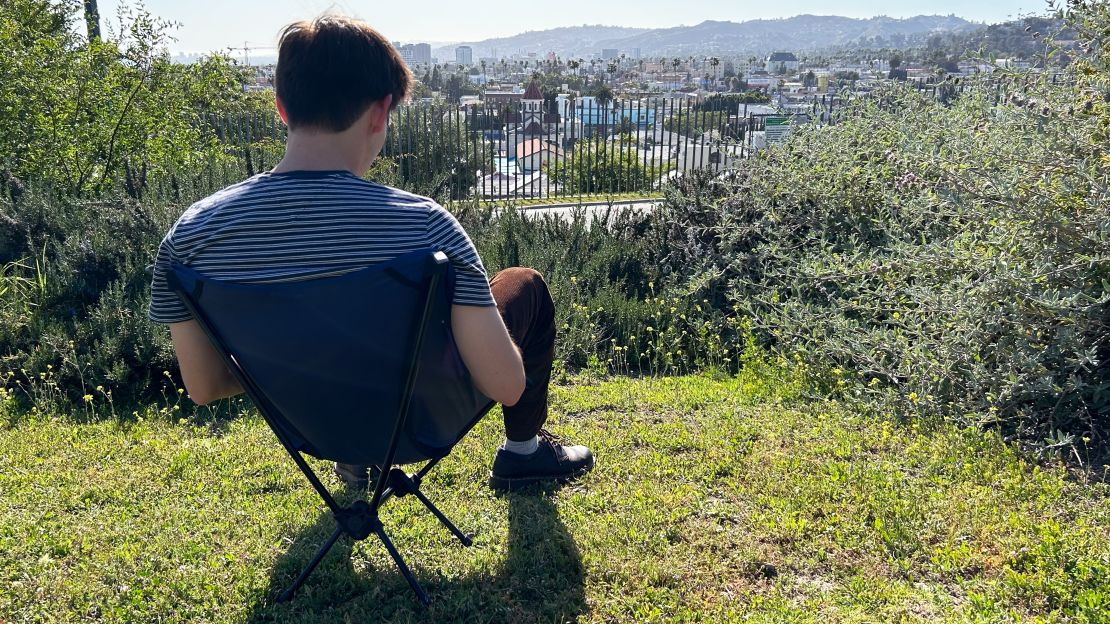 Man sitting in REI Co-op Flexlite Camp Chair in front of view of Los Angeles