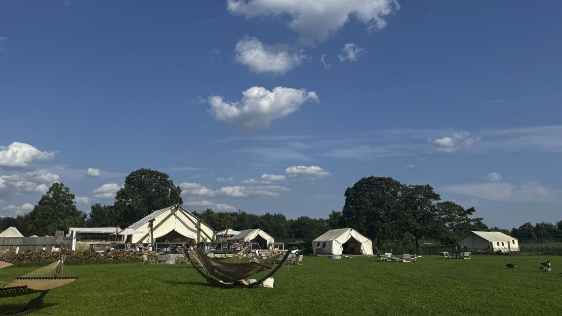 Landscape view of hammocks and tents on grass.