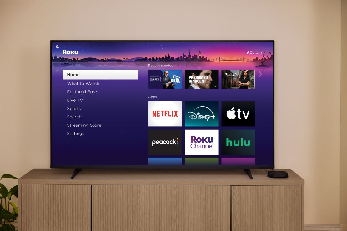 The Roku Ultra 2024 is connected to a TV on a countertop that's got the Roku home screen up