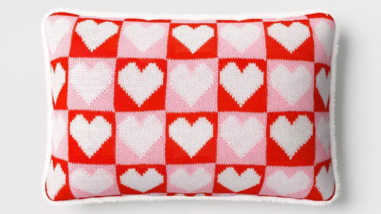 A rectangular checkered pillow with hearts on it.
