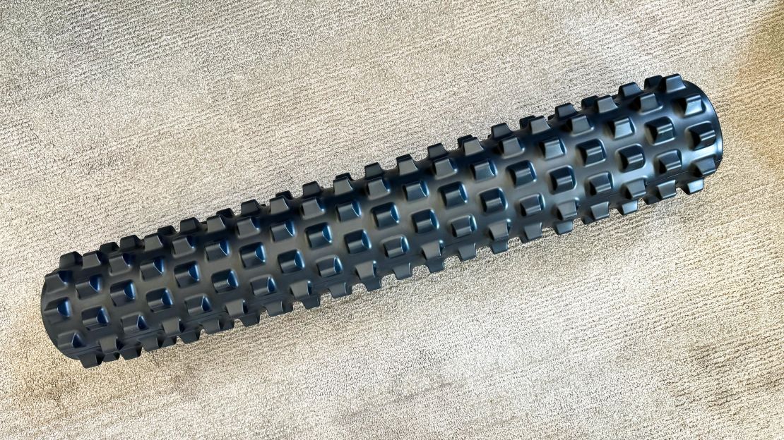 A RumbleRoller 31-Inch Xtra Firm Textured Foam Roller on a carpet surface.